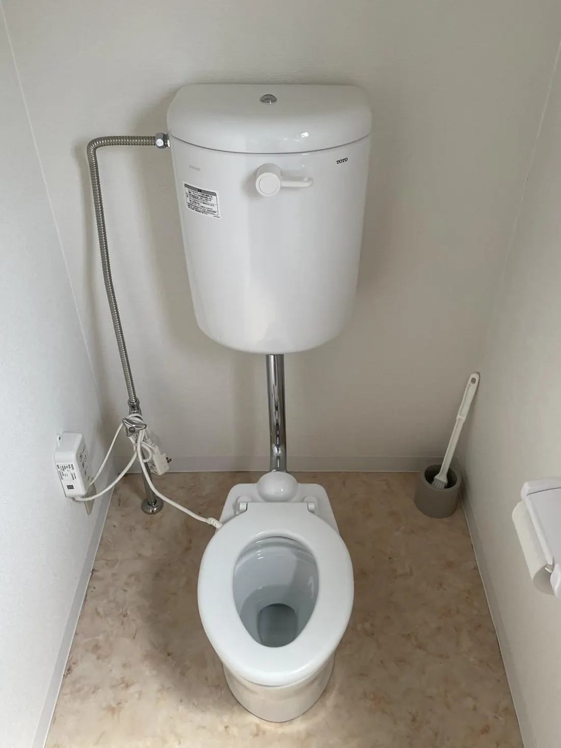 子ども用トイレの内部。便器とトイレットペーパー、掃除用ブラシが置かれている