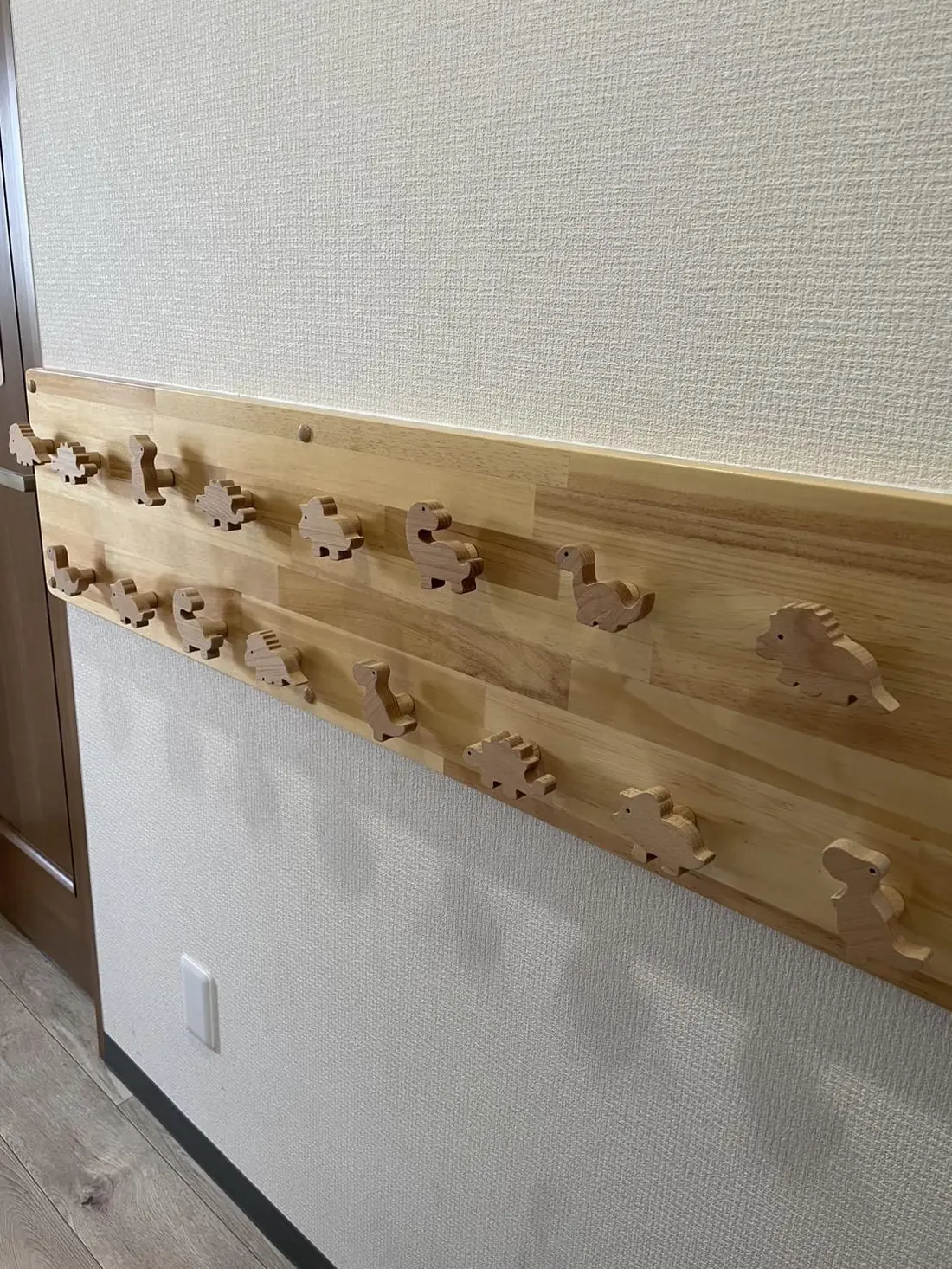 恐竜の形をした木製フックが並ぶタオル掛け