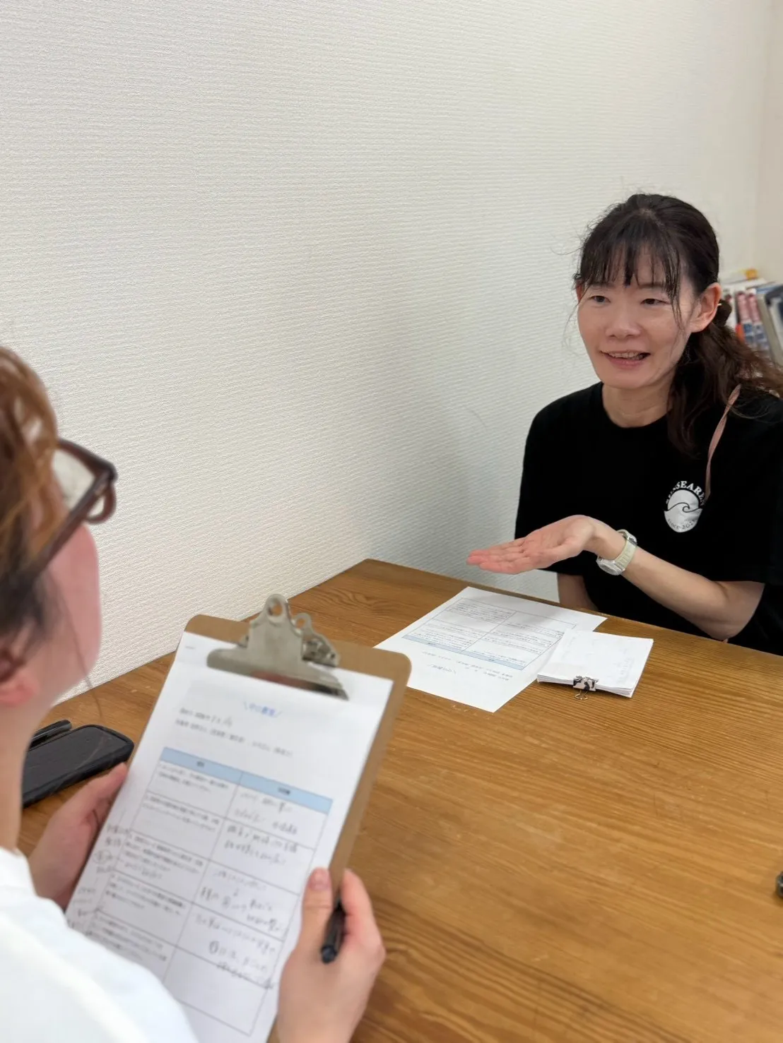 机をはさんで笑顔で話すスタッフと、手元の用紙に書き込みながら聞き取りをするスタッフ