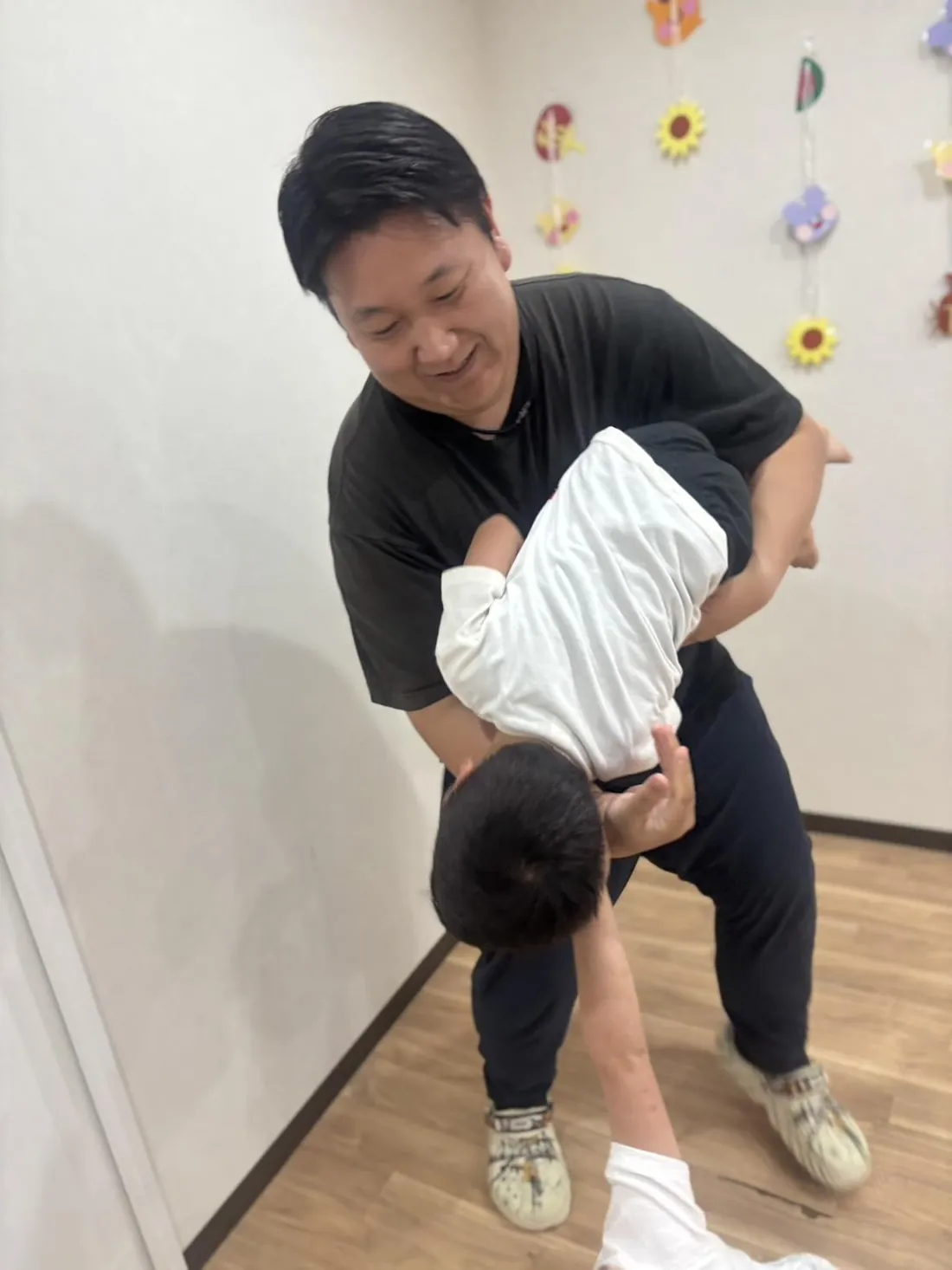 子どもを抱き上げて笑顔で遊ぶスタッフ